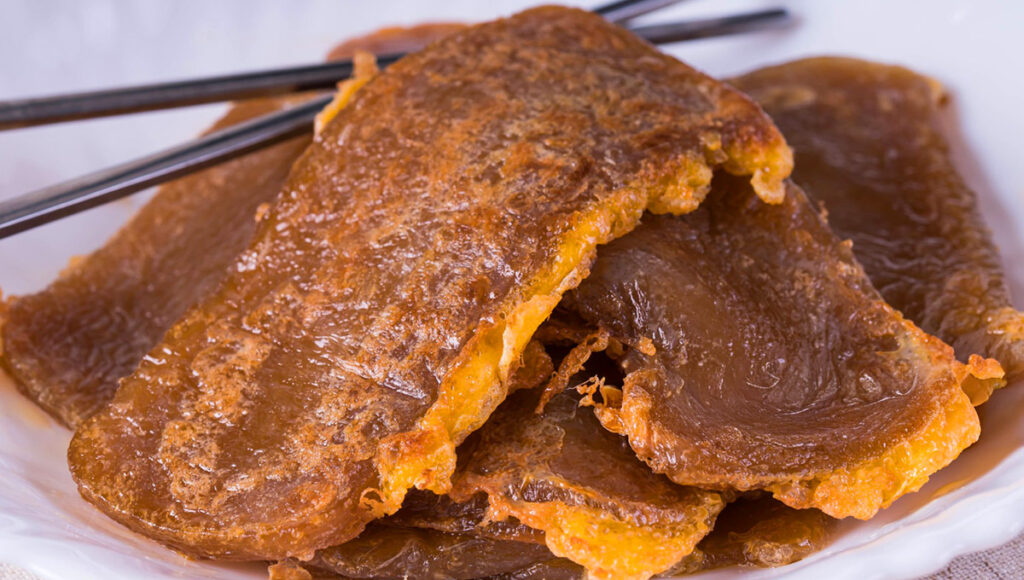 A piece of Tikoy, a sticky glutinous rice cake covered with egg, a traditional Filipino Christmas food symbolizing good fortune.