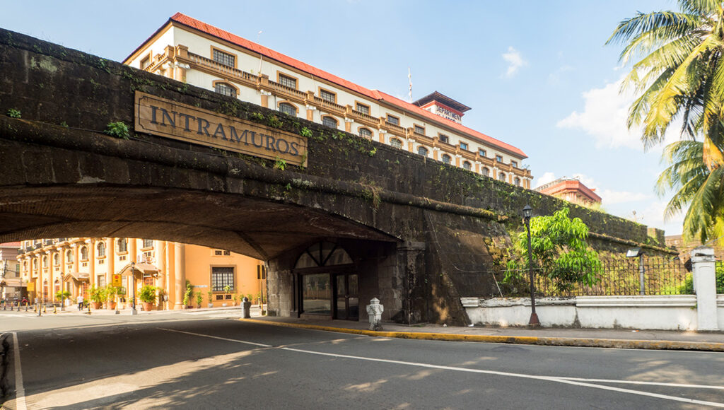 The historical stone wall and arched gateway of Intramuros in Manila, with a sign overhead, a significant landmark and one of the essential things to do in Manila.