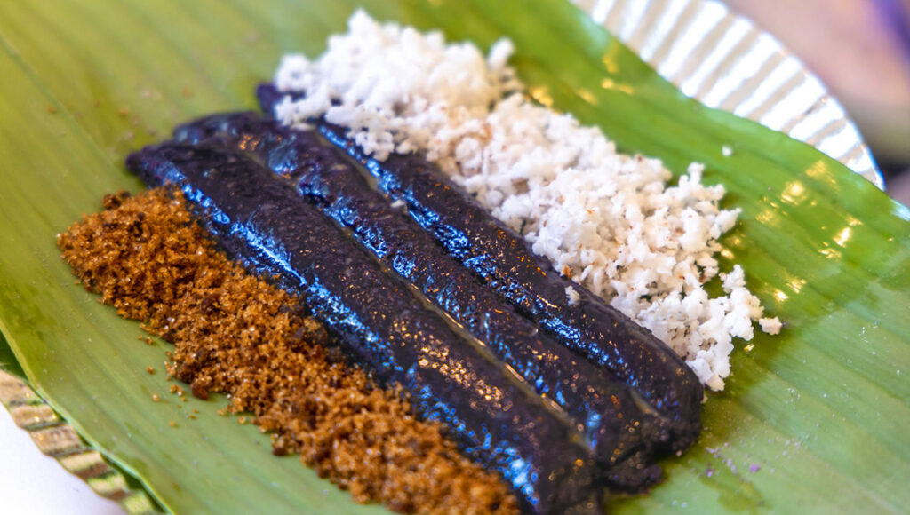 Puto bumbong, a beloved piece of Filipino Christmas food wrapped in banana leaves and topped with coconut.