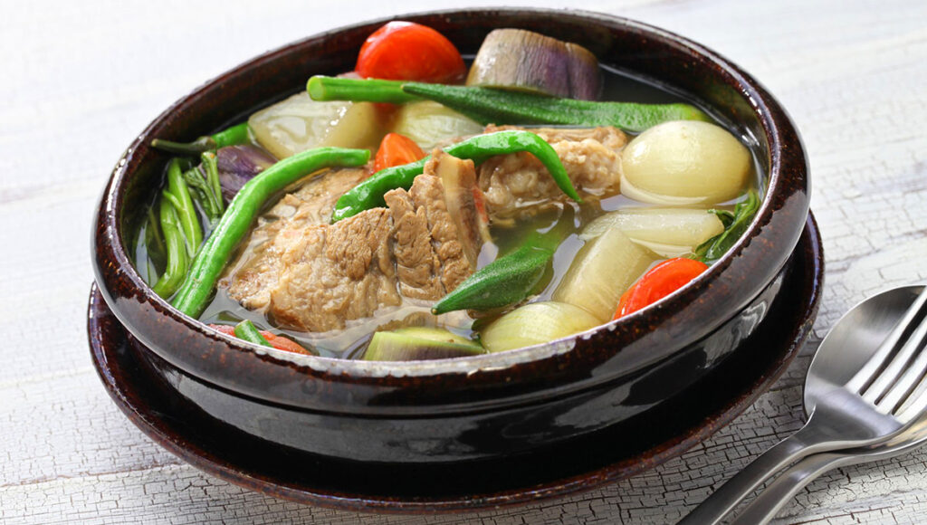 A bowl of sinigang na baboy, a sour pork soup that complements rich Filipino Christmas food during Noche Buena