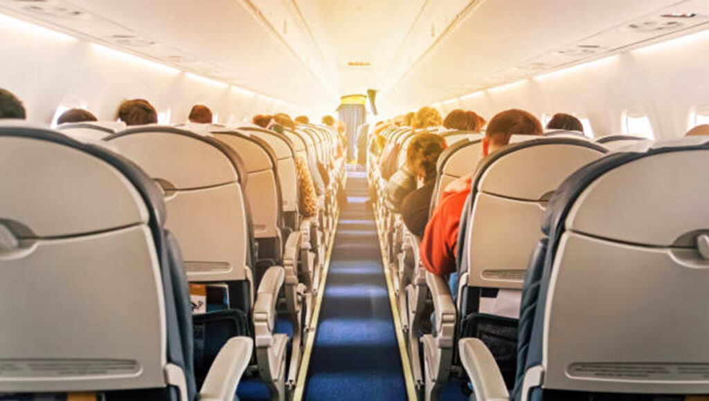 Interior view of a commercial airplane cabin with rows of seats and aisle, representing the comfortable experience of flying on direct flights to Philippines from UK.