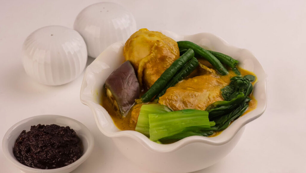 A serving of Kare-Kare, a traditional Filipino Christmas food of meat in a rich, nutty peanut sauce served with bagoong