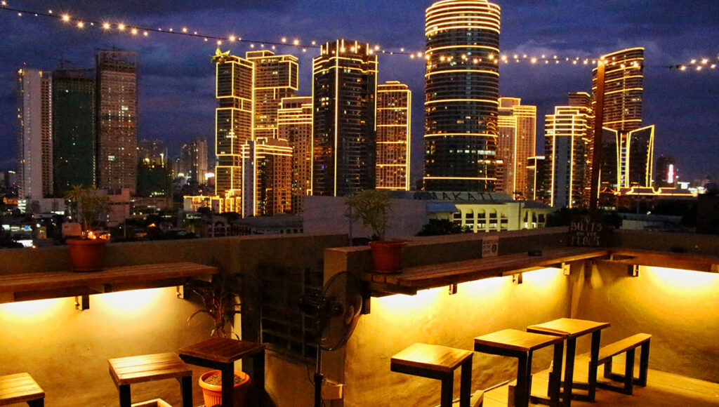 Manila city skyline at night with glowing skyscrapers and lights, showcasing one of the vibrant things to do in Manila, experiencing its nightlife and rooftop views.