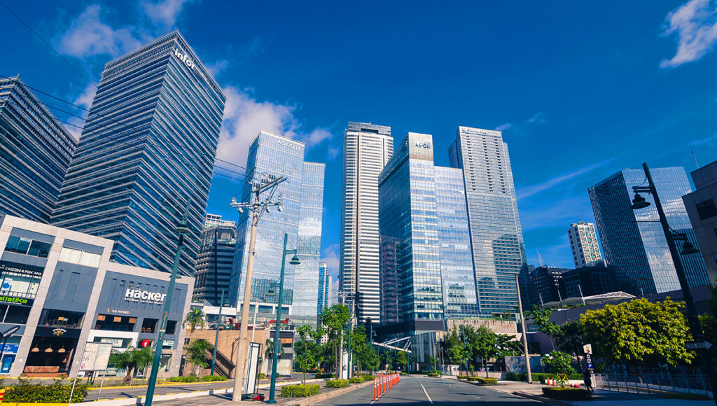 Modern, sleek glass skyscrapers on a wide street in Bonifacio Global City (BGC), a trendy area for where to stay in Manila.