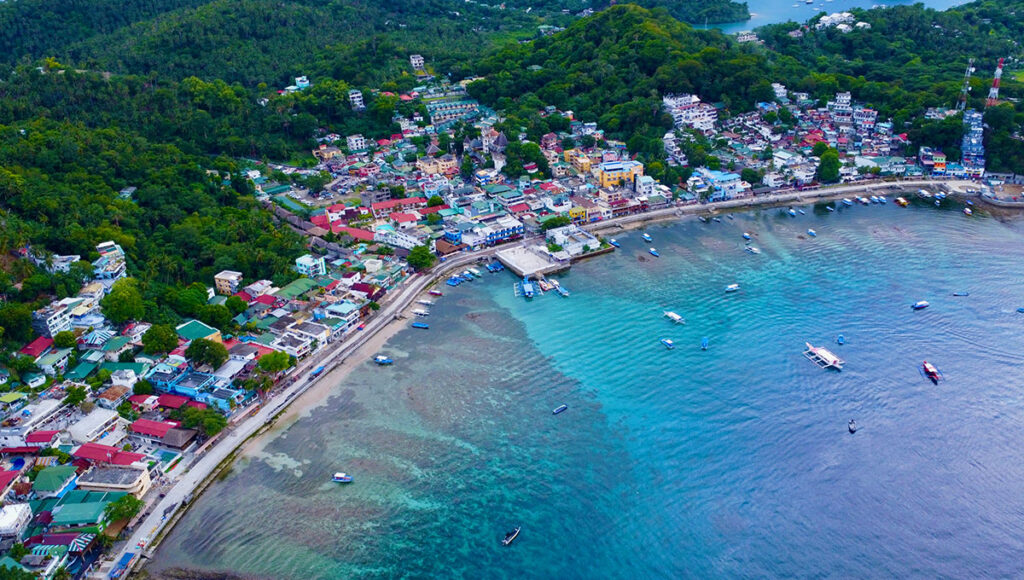 Coastal view of the colourful waterfront town and harbour of Puerto Galera, Mindoro, known globally for Philippines scuba diving and resorts.