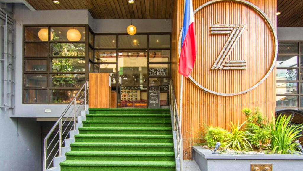 The entrance to Z Hostel in Makati with green turf steps and a wooden facade, a popular budget choice for where to stay in Manila.