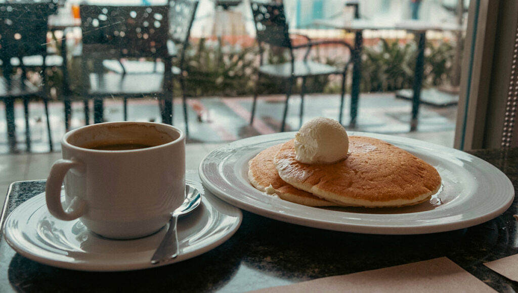 Breakfast with pancakes and coffee at a cafe with harbor view, similar to cozy brunch spots at the best restaurants in Manila.