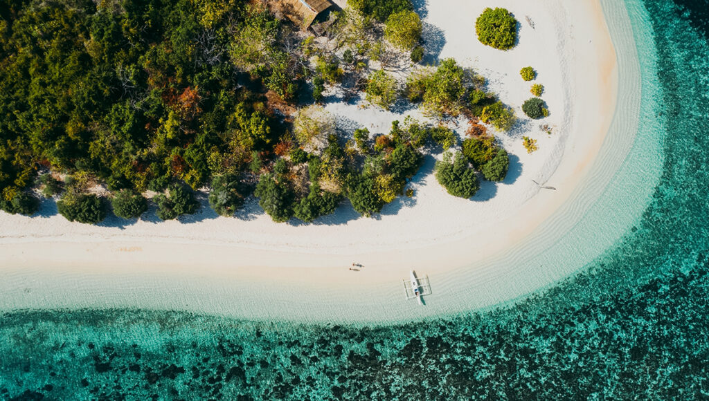 Smiling couple walking hand‑in‑hand on a secluded tropical beach, a scene that captures why travel advice Philippines recommends remote coastal escapes.
