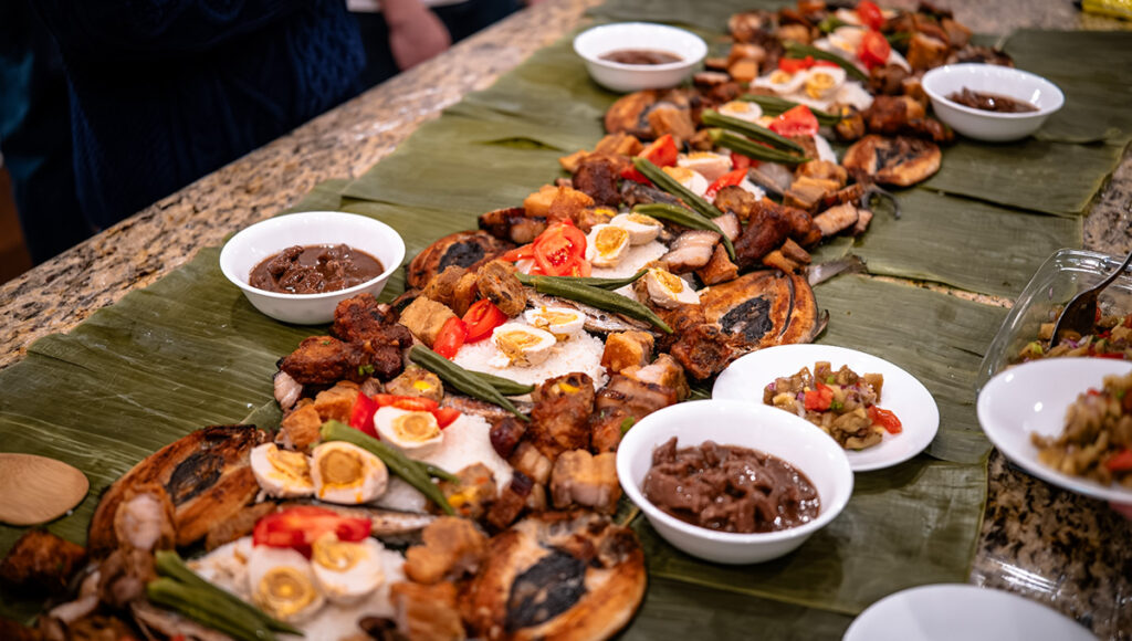 Colorful spread of dishes for a communal Boodle Fight Philippines, featuring rice, seafood, and meats.