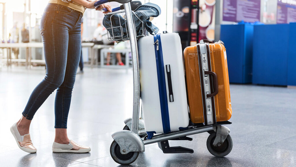 Woman walking through a busy airport terminal carrying multiple suitcases, demonstrating Philippines Airlines baggage allowance for checked and carry-on bags