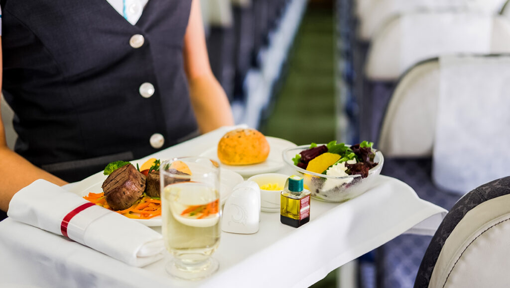 Air hostess carrying trays of meals, representing the premium experience of Philippine Airlines food.
