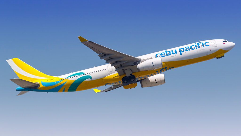 An aerial view of a Cebu Pacific plane flying above clouds, illustrating the smooth travel experience with the best airline to fly to Philippines from UK.