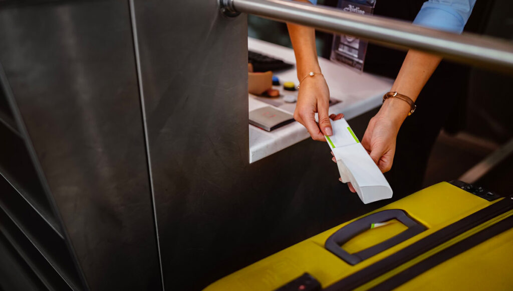 An airport check-in counter employee attaching a luggage tag to a traveler’s bag, reflecting Philippines Airlines baggage allowance procedures and weight limits