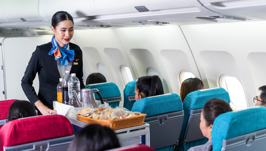 Traveller enjoying in-flight dining with Philippine Airlines food served by a flight attendant.