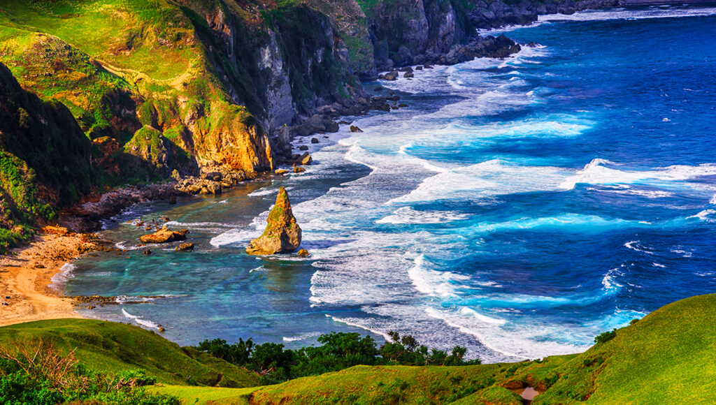 This iconic Batanes tourist attraction highlights Rakuh a Payaman, famously known as Marlboro Country, where wide-open grasslands stretch across the hills like a natural carpet. The area looks endless, with soft green slopes and a dramatic sky in the distance, often filled with grazing cows and fresh mountain air that makes the scenery feel cinematic and timeless.