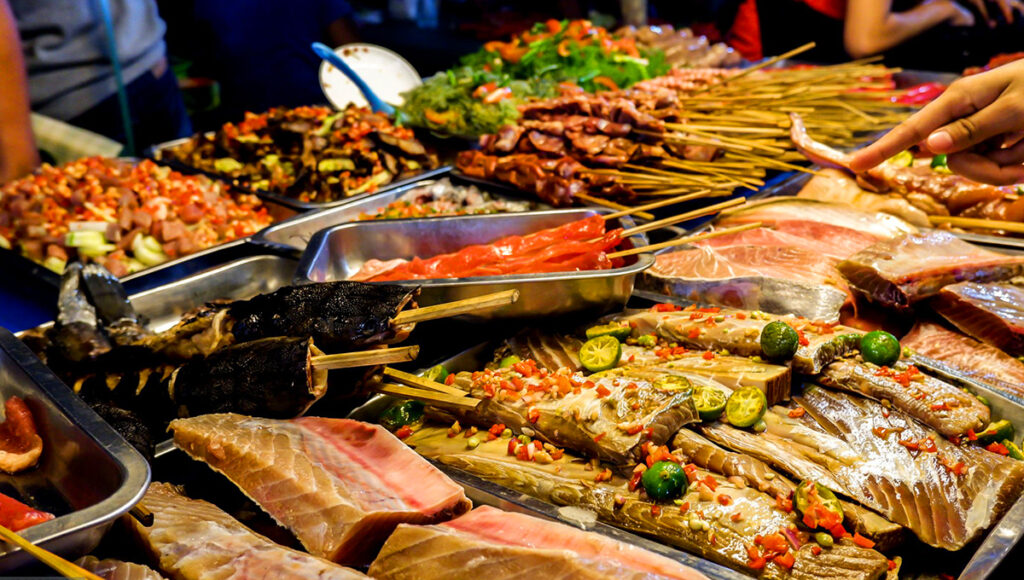 Different seafood and meat choices at a Filipino night market, showcasing affordable cost of living in Philippines local food culture