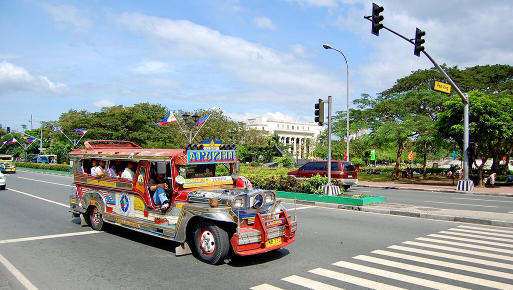 Jeepney taxi driving through downtown Manila showing affordable public transport and cost of living in Philippines city life.