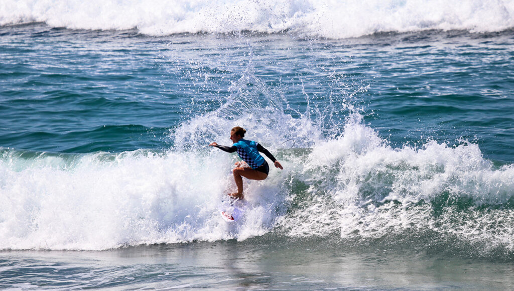 A surfer riding a wave on a sunny beach.