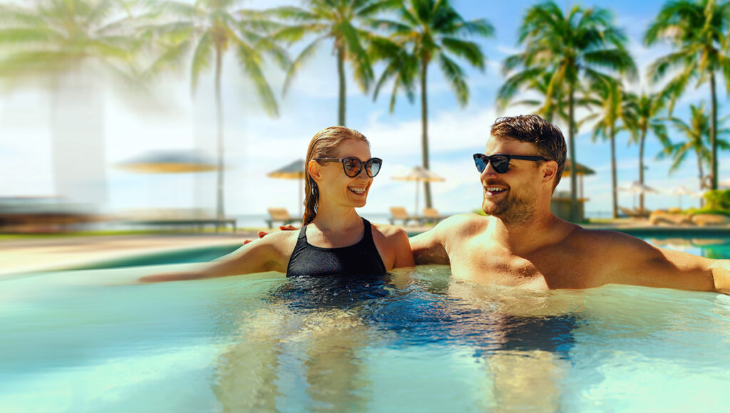 Couple relaxing in a hot tub by a swimming pool at a tropical resort, illustrating affordable cost of living in Philippines leisure lifestyle.