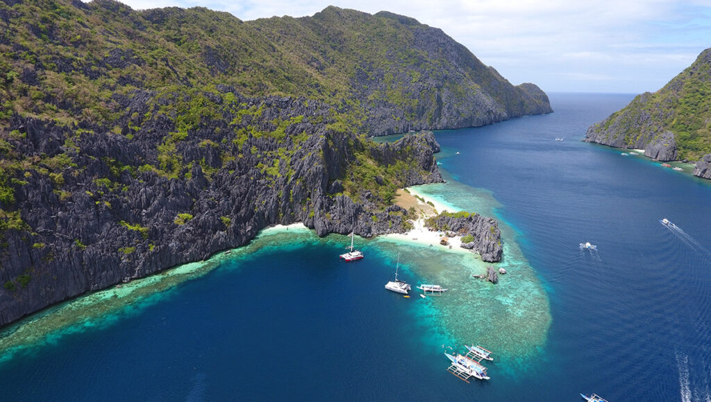 An aerial view of turquoise waters and limestone cliffs in El Nido, Palawan, used to help travelers visualize how long to spend in the Philippines for an island-hopping adventure.