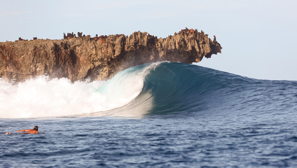 A powerful, barreling wave breaking against a rugged rock formation, showcasing the advanced reef breaks found at premier siargao surf spots.