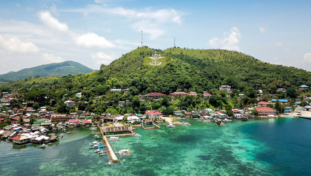 A coastal view of Culion Island, featuring clear green waters and the mountainous backdrop found near Palawan beaches.