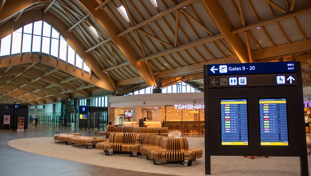 The modern, high-ceiling interior of Clark International Airport terminal with wooden arches, located near the Manila airport lounge areas for departing passengers.