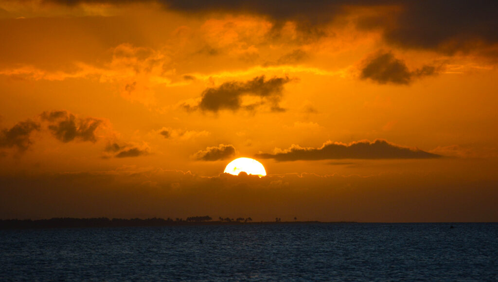 A dramatic tropical sunset over the ocean, reflecting the hazy and humid conditions typical of Philippines weather May as the monsoon season approaches.