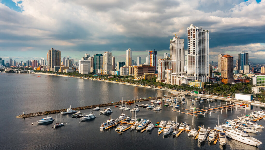 An aerial view of yachts docked at the Manila Yacht Club with the city skyline in the background under the hazy afternoon Philippines weather in March.