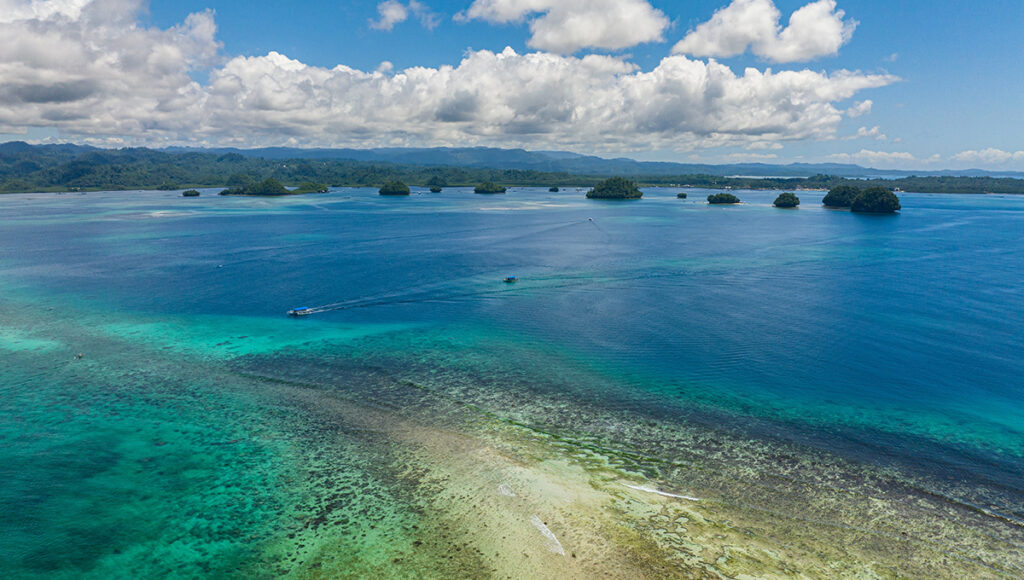 Aerial view of scattered tropical islets and coral reefs, a scenic place to visit in Surigao for island hopping.