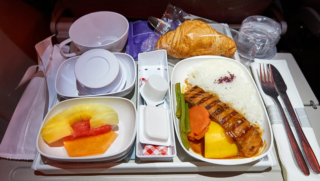 A tray of airplane food on a long-haul flight, representing the dining standards often compared in Qatar Airways vs Emirates economy class reviews.