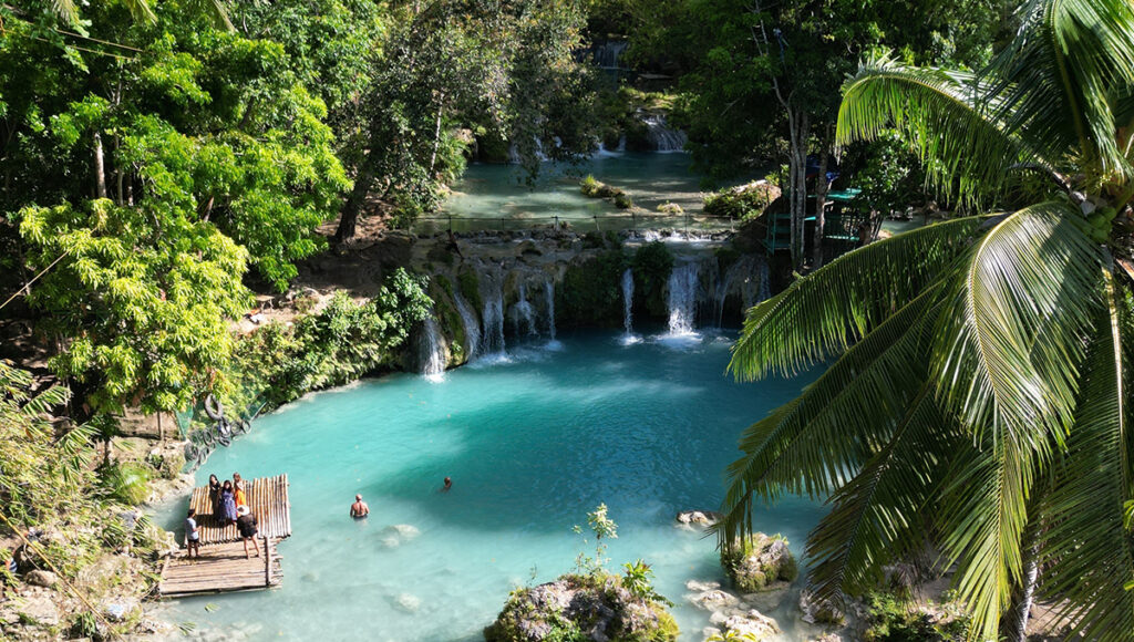 Tourists enjoying a bamboo raft at the turquoise Cambugahay Falls in Siquijor, a hidden gem often included in a 2 weeks in Philippines itinerary.