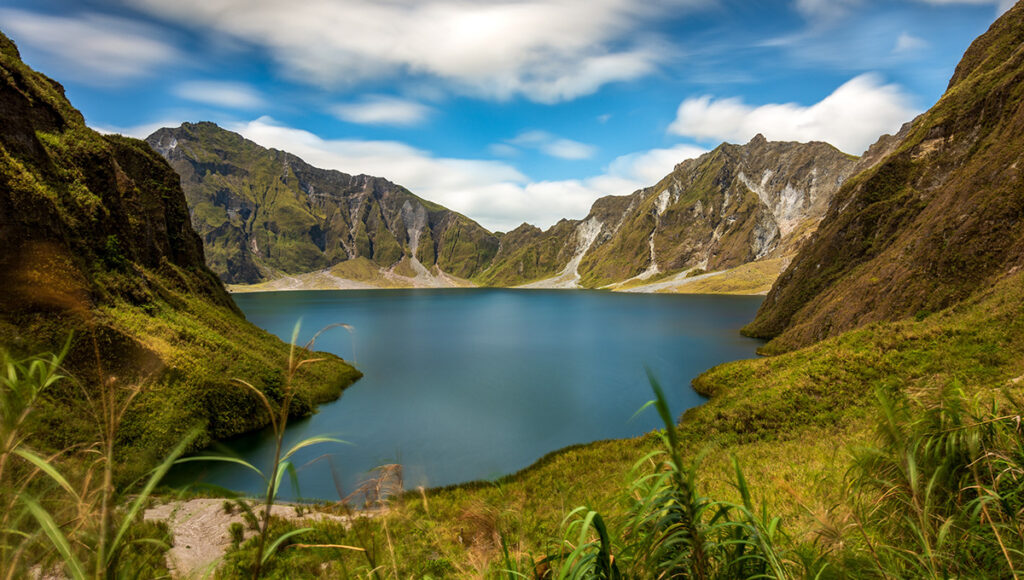 The stunning turquoise crater lake of Mount Pinatubo surrounded by jagged volcanic peaks, a top destination for hiking-focused day trips from Manila.