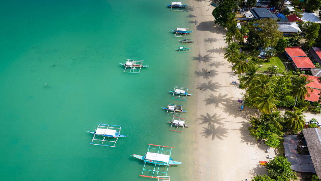 Top-down aerial shot of traditional boats in Port Barton beach, capturing the essence of things to do in Palawan.