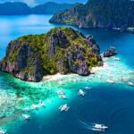 Aerial view of turquoise waters and limestone cliffs in El Nido, Palawan, showcasing the tropical environment to consider when deciding what to pack to Philippines.