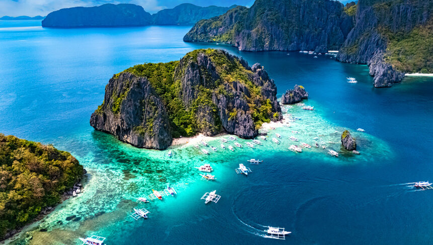Aerial view of turquoise waters and limestone cliffs in El Nido, Palawan, showcasing the tropical environment to consider when deciding what to pack to Philippines.