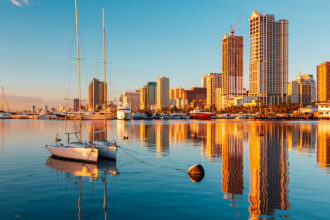 Sunset over the Manila Bay skyline with sailboats on calm water; a great scene after arriving at one of the hotels near Manila airport.