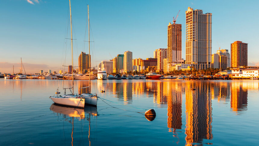 Sunset over the Manila Bay skyline with sailboats on calm water; a great scene after arriving at one of the hotels near Manila airport.