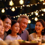 A happy, multi-generational Filipino family is smiling together while enjoying an outdoor dinner under warm string lights, capturing the spirit of Filipino Christmas traditions.