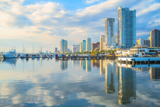 A panoramic view of the Manila skyline at sunset, showcasing modern buildings and Manila Bay, perfect for highlighting things to do in Manila for travellers.