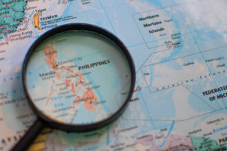 Detailed geographical map of the Philippines under a magnifying glass, illustrating the archipelagic nature of the country. A visual aid for discovering fascinating fun facts about the Philippines and its unique location in Southeast Asia.