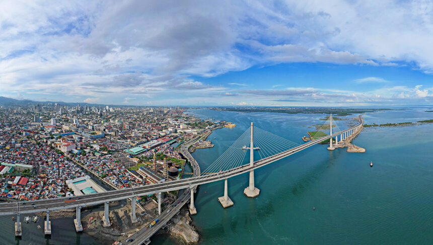 Aerial panoramic view of the massive Cebu City skyline, modern cable-stayed bridge, and harbor, showing the urban side of where to stay in Cebu.