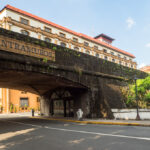 The historical stone wall and arched gateway of Intramuros in Manila, with a sign overhead, a significant landmark and one of the essential things to do in Manila.