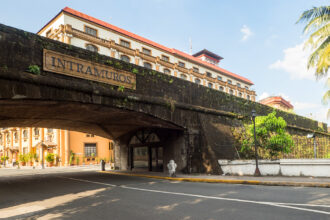 The historical stone wall and arched gateway of Intramuros in Manila, with a sign overhead, a significant landmark and one of the essential things to do in Manila.