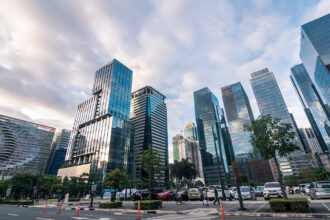 Low-angle view of ultra-modern, glass skyscrapers in Bonifacio Global City (BGC), Taguig, one of the premier business and lifestyle districts in the Metro Manila area. The clean, well-lit street and modern design contribute to the perception of a safe and secure area when asking, is Manila safe?