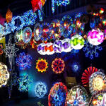 A vivid nighttime display of large, brightly illuminated Parol lanterns and other Christmas lights, including a Nativity scene, symbolises a key element of Filipino Christmas traditions.