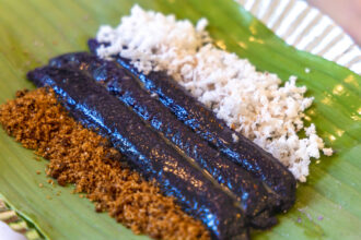 Puto bumbong, a beloved piece of Filipino Christmas food wrapped in banana leaves and topped with coconut.