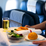 Flight attendant serving a delicious meal onboard, showcasing Philippine Airlines food.