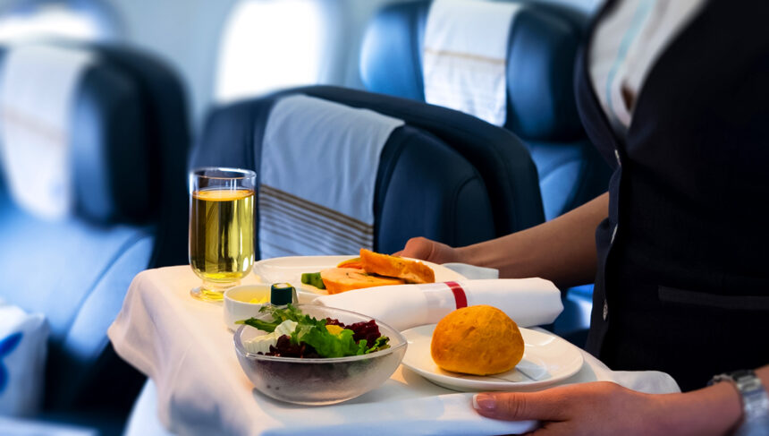 Flight attendant serving a delicious meal onboard, showcasing Philippine Airlines food.