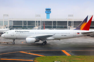 Philippine Airlines airplane parked at Manila airport, with passengers preparing their luggage according to Philippines Airlines baggage allowance rules.